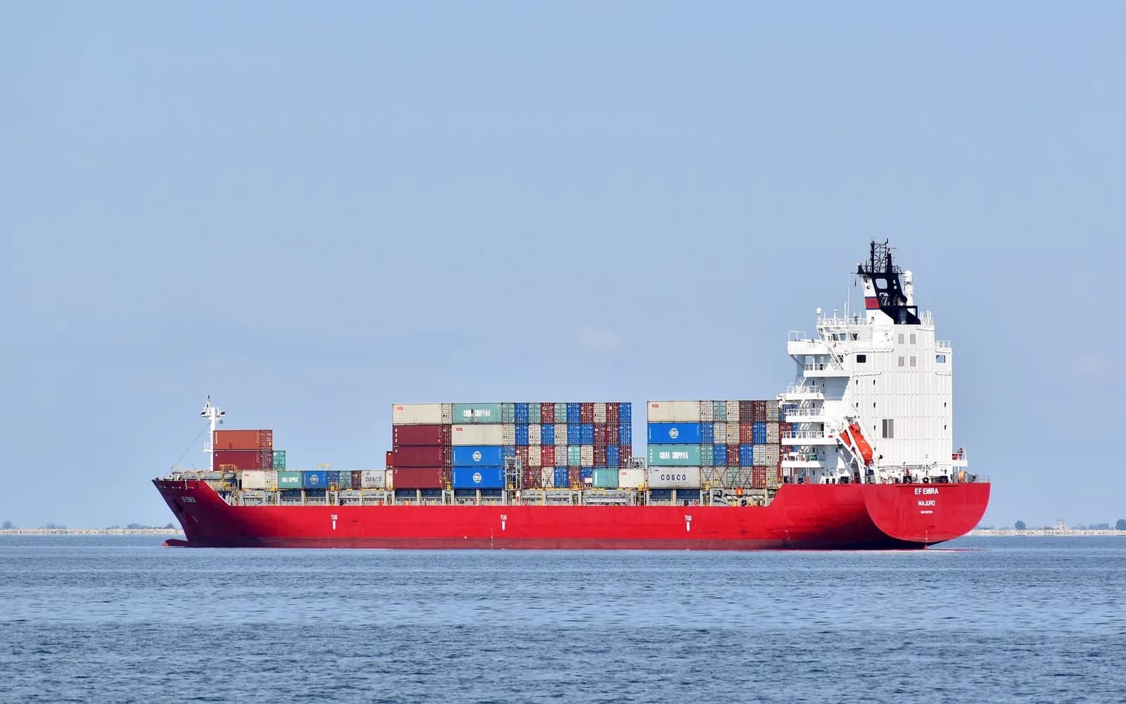 Red container vessel sailing on open water